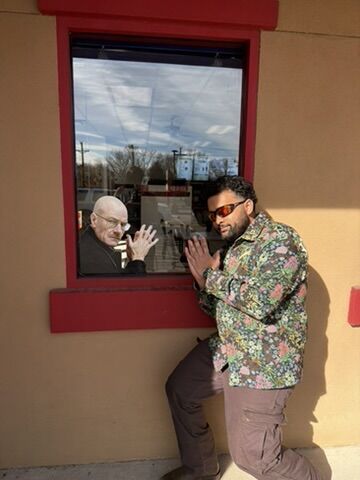 Tanmay mirroring a Colonel Sanders figure in a restaurant window